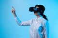 Woman exploring digital interface with VR headset, using coordinated gestures on bright blue background Royalty Free Stock Photo