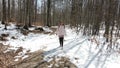 Woman exploring a forest with naked trees and some snow