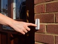 Woman extends her hand to ring doorbell