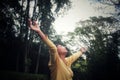 Woman with eyes closed, hands raised showing a thankful heart gesture on green park nature background. Forgiving, grateful,