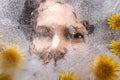 Woman eyes  through transparent ice with dandelions flowers Royalty Free Stock Photo