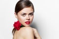 woman face close-up red bites her lip with flower Attractive-looking charm naked shoulders clear skin red lips Royalty Free Stock Photo
