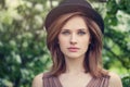 Woman face closeup outdoor portrait. Pretty girl in hat on greenery foliage background