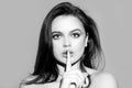 Woman face, finger on her lips. Silence gesture. Portrait of sensual young female model.