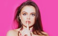 Woman face, finger on her lips. Silence gesture. Portrait of sensual young female model.