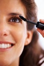 Woman, face and mascara with smile for beauty, cosmetics and facial skincare with glow or closeup. Person, happy and eye