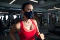 Woman with face mask doing exercise on treadmill in gym, coronavirus concept.