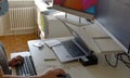 A woman in face mask in home office during coronavirus typing on a keyboard with one hand and using a mouse with the other.