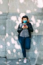 Woman with a face mask leaning against the wall using her smartphone