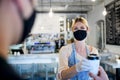 Woman with face mask serving customer, shop open after lockdown quarantine.