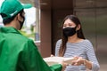 Woman with face mask take pizza from driveryman