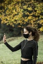 Woman with face mask taking video call. Giving lectures while working out during covid-19