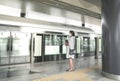 Woman with face mask on waiting for train at the platform of a subway station Royalty Free Stock Photo