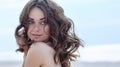 Woman face Portrait on the beach. Happy beautiful curly-haired girl close-up, the wind fluttering hair. Spring portrait on the bea Royalty Free Stock Photo