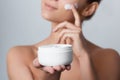 Woman Face Skin Care. Portrait Of Attractive Young Female Applying Cream And Holding Bottle.