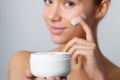 Woman Face Skin Care. Portrait Of Attractive Young Female Applying Cream And Holding Bottle. Royalty Free Stock Photo