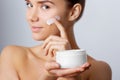 Woman Face Skin Care. Portrait Of Attractive Young Female Applying Cream And Holding Bottle. Royalty Free Stock Photo