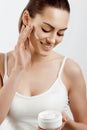 Woman Face Skin Care.  Woman Face Skin Care. Portrait Of Attractive Young Female Applying Cream  And Holding Bottle. Closeup Of Royalty Free Stock Photo