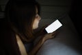 Woman face using cellphone secretly on bed in the dark at night. Asian girl in a dark room with mobile smart phone. Young Royalty Free Stock Photo