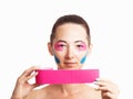 Woman with facelift applique holding roll of kinesiology tape.