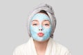 Woman with facial clay mask at spa salon or at home, skincare theme. Girl removes alginate cosmetic mask. Face mask, spa