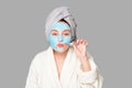 Woman with facial clay mask at spa salon or at home, skincare theme. Girl removes alginate cosmetic mask. Face mask, spa