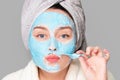 Woman with facial clay mask at spa salon or at home, skincare theme. Girl removes alginate cosmetic mask. Face mask, spa