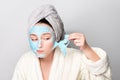 Woman with facial clay mask at spa salon or at home, skincare theme. Girl removes alginate cosmetic mask. Face mask, spa