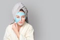 Woman with facial clay mask at spa salon or at home, skincare theme. Girl removes alginate cosmetic mask. Face mask, spa