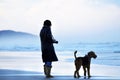 Woman and faithful friend dog alone on stunning beach watching ocean Royalty Free Stock Photo