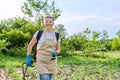 Woman farmer with backpack hand sprayer protecting young potato plants