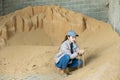 Woman farmer checking quality of soybean husk for livestock feeding