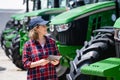 Woman farmer with a digital tablet on the background of an agricultural tractor. Royalty Free Stock Photo