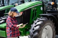 Woman farmer with a digital tablet on the background of an agricultural tractor Royalty Free Stock Photo