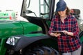 Woman farmer with a digital tablet on the background of an agricultural tractor Royalty Free Stock Photo