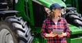 Woman farmer with a digital tablet on the background of an agricultural tractor. Royalty Free Stock Photo