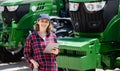 Woman farmer with a digital tablet on the background of an agricultural tractor.s Royalty Free Stock Photo