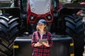 Woman farmer with a digital tablet on the background of an agricultural tractor Royalty Free Stock Photo