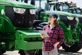 Woman farmer with a digital tablet on the background of an agricultural tractors. Royalty Free Stock Photo