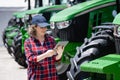 Woman farmer with a digital tablet on the background of an agricultural tractors. Royalty Free Stock Photo