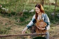 A woman farmer smiles and pours food for the birds into a bird feeder from a bowl at an outdoor farm to raise healthy Royalty Free Stock Photo