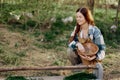 A woman farmer smiles and pours food for the birds into a bird feeder from a bowl at an outdoor farm to raise healthy Royalty Free Stock Photo