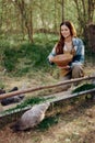 Woman farmer smiles and pours food for the birds at the bird feeder at the chicken farm Royalty Free Stock Photo