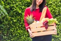 Woman farmer standing hold full fresh food raw vegetables fruit in a wood box Royalty Free Stock Photo