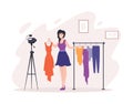 Woman fashion stylist blogger shooting video content with hanging clothes use camera on tripod