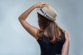 Woman in fashionable hat and black shirt posing in a half turn from the back stylishly on gray background in studio Royalty Free Stock Photo