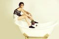 Woman sitting on empty, vintage bathtub with lilac bunch Royalty Free Stock Photo