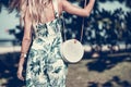 Woman with fashionable stylish rattan bag and silk scarf outside. Tropical island of Bali, Indonesia. Rattan handbag and