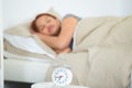 woman fast asleep alarm clock in foreground