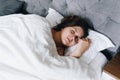 Young woman fast asleep sleeping in her bed on white bed linen